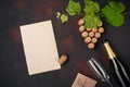 Bottle of champagne, grape bunch of cork with leaves, paper sheet, wineglass on rusty background