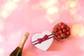 Bottle of champagne, heart shape gft box and fresh strawberry on pink background Royalty Free Stock Photo