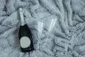 A bottle of champagne and two glasses against the background of gray fur plaid Royalty Free Stock Photo