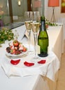 Bottle of champagne, two glasses and chocolate strawberries on a tray with rose petals Royalty Free Stock Photo