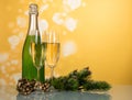 Bottle of champagne, two glasses, decorated pine branches on yellow Royalty Free Stock Photo