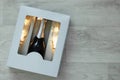 A bottle of champagne and two glasses with a luminous garland in a cardboard box. On white wooden background Royalty Free Stock Photo