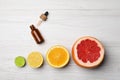 Bottle of citrus essential oil and fresh fruits on white wooden table, flat lay. Space for text Royalty Free Stock Photo