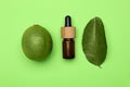 Bottle of citrus essential oil, fresh lime and leaf on green background, flat lay Royalty Free Stock Photo