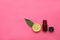 Bottle of citrus essential oil and fresh lime on pink background, flat lay. Space for text Royalty Free Stock Photo