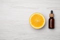 Bottle of citrus essential oil and fresh orange on white wooden table, flat lay. Space for text Royalty Free Stock Photo