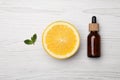 Bottle of citrus essential oil and fresh orange on white wooden table, flat lay Royalty Free Stock Photo