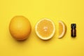 Bottle of citrus essential oil and fresh oranges on yellow background, flat lay Royalty Free Stock Photo