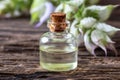 A bottle of clary sage essential oil with blooming plant