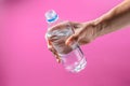 Bottle of clean drinking water in the hand of a man on a pink background Royalty Free Stock Photo