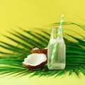 Bottle of coconut water and fresh ripe fruits on yellow background. Summer food concept. Vegetarian, vegan, detox drink Royalty Free Stock Photo