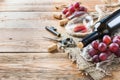 Bottle, corkscrew, glass of red wine, grapes on a table