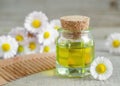Bottle of cosmetic chamomile oil and wooden hair comb