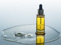 The bottle of cosmetic oil stands on the water background with splash