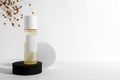 Bottle of cosmetic product, dried flowers and round podiums on white background, space for text
