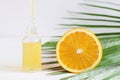Bottle of cosmetic skincare serum with dropper, orange and palm leaf. Citrus essential oil with Vitamin C. Serum is Royalty Free Stock Photo