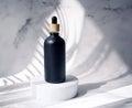 A bottle with cosmetics for the face on the podium, on a white background with shadows from the leaves of a palm tree. Skin care