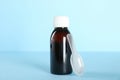 Bottle of cough syrup and dosing spoon on light blue background Royalty Free Stock Photo