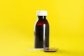 Bottle of cough syrup and dosing spoon on yellow background Royalty Free Stock Photo