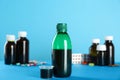 Bottle of cough syrup and measuring cup on light blue background Royalty Free Stock Photo