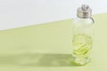 A bottle of cucumber water on a light green background. Minimalistic creative concept. Copy space Royalty Free Stock Photo