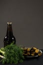 A bottle of dark beer and a plate of fish. On a dark background Royalty Free Stock Photo