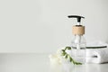 Bottle with dispenser cap, towel and beautiful flower on white table. Space for text Royalty Free Stock Photo