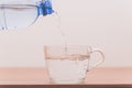 Person pouring water from a plastic bottle into a glass cup Royalty Free Stock Photo