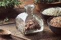 Bottle of dry medicinal bark and herbs for making healing infusion or tincture. Bowls of dried medicinal plants and wooden mortar