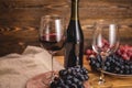 Bottle of dry red wine with a glass and a bunch of grapes on a wooden table. Concept of viticulture and winemaking Royalty Free Stock Photo