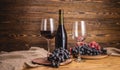 Bottle of dry red wine with a glass and a bunch of grapes on a wooden table. Concept of viticulture and winemaking Royalty Free Stock Photo