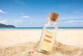 Bottle with a empty paper message on  sand beach over blue sea and sun light. Royalty Free Stock Photo