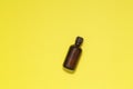 Bottle of essential aroma oil on yellow background. Copy space.