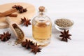 Bottle of essential oil, anise and seeds on white wooden table Royalty Free Stock Photo