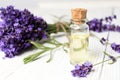 A bottle of essential oil and a bouquet of fresh lavender flowers on a white wooden background. A set of spa treatments and Royalty Free Stock Photo