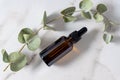 Bottle with essential oil and eucalyptus branches on marble baclground. Skin care and healthy treatment for the face and body