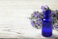 Bottle of essential oil and  flowers on white wooden table. Space for text Royalty Free Stock Photo