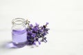 Bottle of essential oil and lavender flowers on white wooden table. Space for text Royalty Free Stock Photo