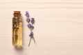 Bottle of essential oil and lavender flowers on white wooden table, flat lay. Space for text Royalty Free Stock Photo