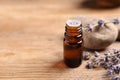Bottle of essential oil and lavender flowers on wooden table, closeup. Space for text Royalty Free Stock Photo