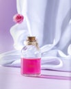 Bottle essential oil or rose water with draped white silk fabric. Spa and aromatherapy cosmetic concept Royalty Free Stock Photo