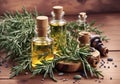 Bottle of essential oil and rosemary herb on a wooden table.