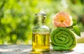 Bottle of essential oil and soft towel. Green soft towel and rose essential oil. Spa concept. Set for Spa treatments.