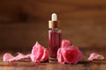 Bottle of essential rose oil and flowers on wooden table Royalty Free Stock Photo