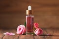 Bottle of essential rose oil and flowers on wooden table Royalty Free Stock Photo