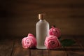 Bottle of essential rose oil and flowers on wooden table Royalty Free Stock Photo