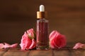 Bottle of essential rose oil and flowers on wooden table Royalty Free Stock Photo