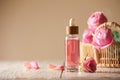 Bottle of essential rose oil and flowers on white wooden table against beige background, space for text Royalty Free Stock Photo