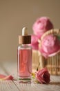 Bottle of essential rose oil and flowers on white wooden table against beige background Royalty Free Stock Photo