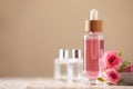 Bottle of essential rose oil and flowers on white wooden table against beige background, space for text Royalty Free Stock Photo